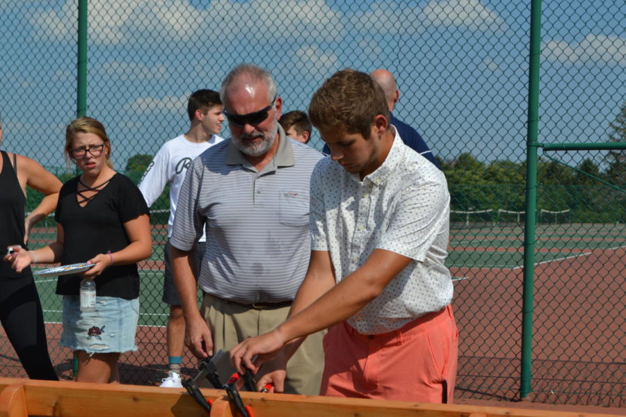 With his father watching, junior Matthew Hopper attaches a plaque to his bench commemorating the life of Brynn Haun at the senior night ceremony for the girls’ tennis team Sept. 20. Hopper chose to create the bench for his Eagle Scout Service Project. “I’ve learned a bunch of stuff from Boy Scouts,” Hopper said. “From living out in the wilderness by yourself to being a better leader, helping younger people, helping older people, just being a better person, you learn life skills.”