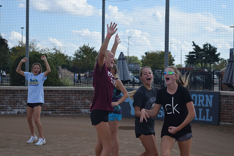 Hands in the air, members of the softball team, celebrate together at home plate. The team played kickball during practice Oct. 5 for some team bonding. “[After team bonding activities] girls who I didn’t feel like I could talk to before I was able to talk with because I now knew we had things in common and could joke around,” Leahy said. “It helped expand my friendships of the team.”