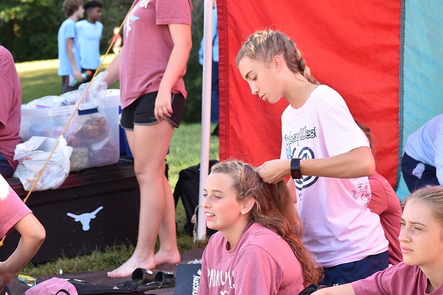 After helping to set up the tent, junior Libby Nickel braids sophomore Anna Butler’s hair in preparation for warm-ups. The girls relaxed at the tent until they began warming up 45 minutes before the start of the race. “I usually sit around and talk with my teammates and try to keep my mind off being nervous. I’m usually pretty calm, but I can get a little anxious to start the warm-up,” Anna said. “Overall, the tent is a nice atmosphere where I can prepare for my race but still have fun with everyone.”
