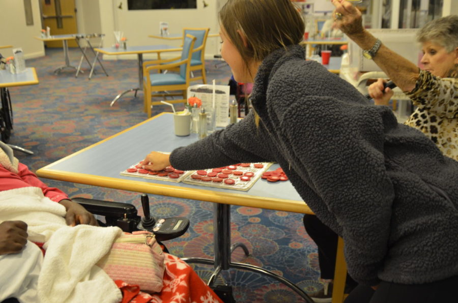 Placing a bingo chip on a resident’s card, sophomore Pryce Ware smiles at the woman’s reaction to winning a number. The varsity cheer squad volunteers at Delmar Gardens every Wednesday night to help the residents play bingo. “It was really good to have conversations with the residents,” Ware said. “They told us that when we come it makes their days, and that throughout the week they talk about how much they enjoy it.”