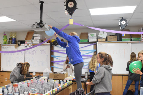 Taping balloons to girls cross country coach Charles Cutelli’s science room, the team fills his room with decorations to celebrate his birthday. The team used one of their many inside jokes with Cutelli to decorate his room. “My favorite part of decorating was spending time with all the girls and just getting to have fun,” sophomore Claire Hardy said. 
