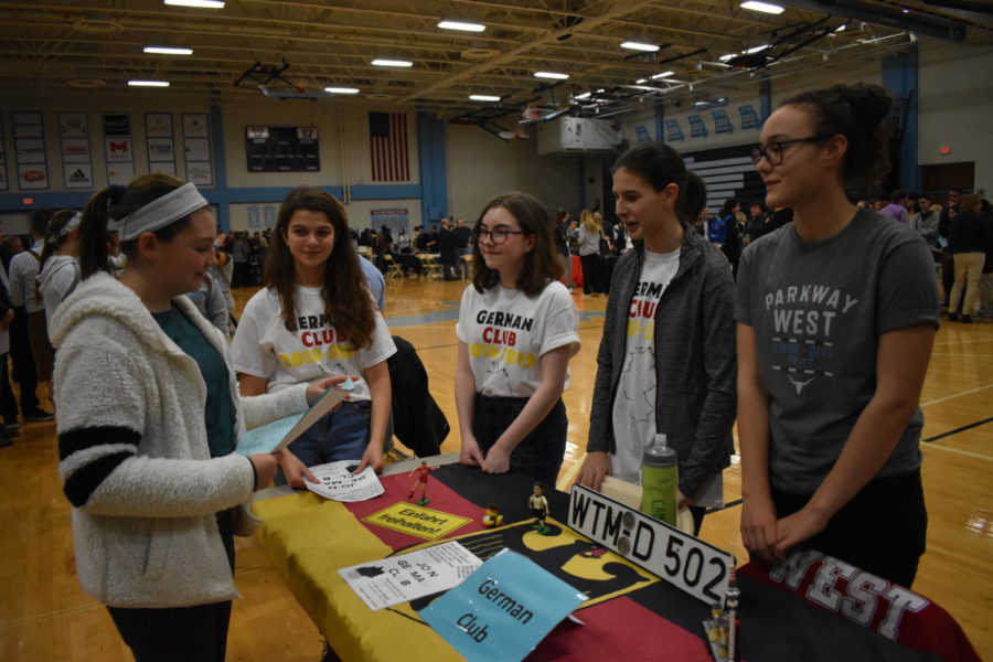 Introducing eighth graders to the highlights of German Club, freshman Anna Csiki-Fejer stands with sophomores Claire Reifschneider and Eva Phillips at the German Club table during Curriculum Night Jan. 15. “We printed out flyers, passed them out and told the students involved in any foreign language about our club because we are open and welcoming to all students, in German or not,” Csiki-Fejer said.