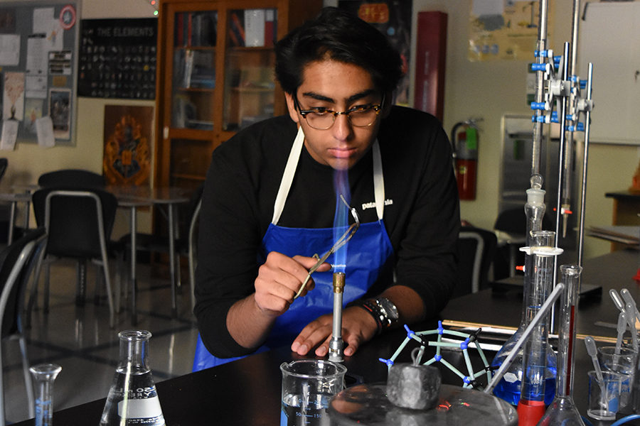 Senior Shahzan Mian holds a strip of potassium over a bunsen burner. Mian has pursued accelerated math and science courses in order to follow a career in medicine. "I’ve worked so hard in high school and I’ve had the stress of the ACT and all of the standardized tests. If I can get the solid guarantee of getting into medical school, which is a very, very difficult thing to do, statistically, I won’t have to stress as much," Mian said.