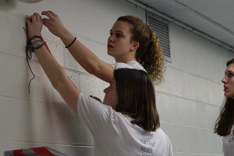Setting up streamers in the pool stand for the night, juniors Lydia Roseman and Claire Lynn tape them to the wall. This has been a long standing tradition. “It was a really exciting night for me because as a junior we were the ones putting the night together so it was cool to see it all fall into place,” Lynn said.