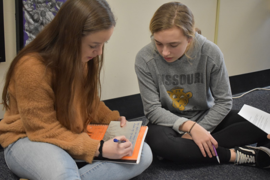In a hands-on activity, freshmen Claire LeDuc and Claire Folkins write curse tablets in Latin 2 . After learning about how Romans used wax tablets to write curses on gravestones of people who wronged them, the class tried to replicate them. “It taught me more in depth about how people used to live back in Rome,” LeDuc said.