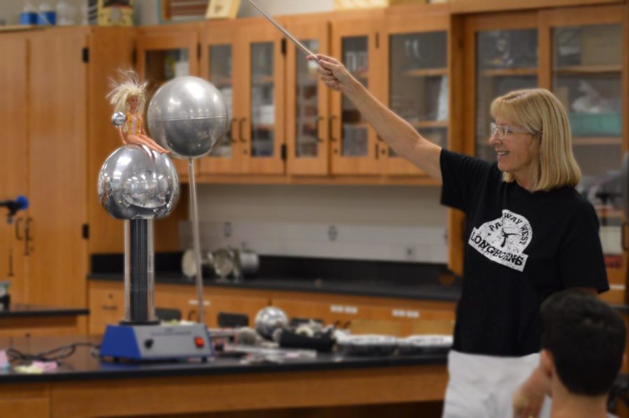 Revolving+a+metal+sphere+around+a+Barbie+doll%2C+physics+teacher+Ellen+Wilke+explains+the+mechanics+behind+electricity.+However%2C+as+much+as+Wilke+enjoys+explaining+electricity%2C+she+would+much+rather+explore+optics.+%E2%80%9CI+really+like+%5Boptics%5D%2C%E2%80%9D+Wilke+said.+%E2%80%9CWave+optics+are+a+really+cool+thing+and+allows+you+to+work+with+material+science%2C+which+is+what+my+undergrad+was%2C+to+work+with+the+crystalline+structure+of+substances.+There%E2%80%99s+so+many+cool+applications+of+optics.+The+basics+will+start+with+mirrors+and+lenses.+Then%2C+it%E2%80%99s+all+about+light+and+the+reflection+of+light%2C+and+the+different+applications+with+lights+and+lasers.%E2%80%9D