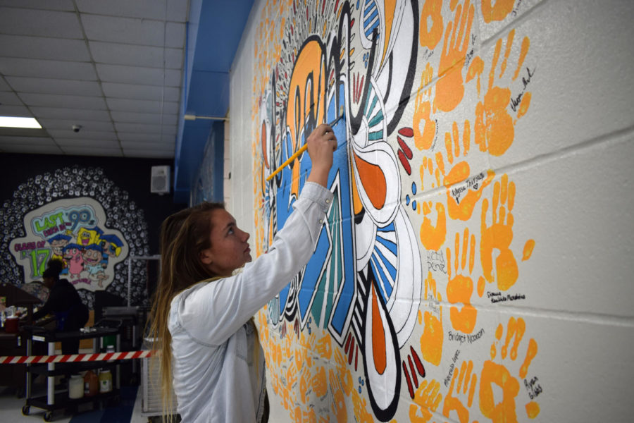 Adding the final touches to the senior mural, senior Bailey Goughenour finishes painting the second design that her and senior Natalie Butler created. After the first design fell through, the artists came together to come up with the ‘Dream Big’ design. “It was just a lot of stress, and it was just really disappointing because we had been cleared. For him to come back and say it’s not anymore was just really sad and hurtful,” Goughenour said. “But after we were turned down, me and Natalie got together, and we were like, ‘what can we do to make this be good?’ We just started brainstorming, and we came up with a new design.”