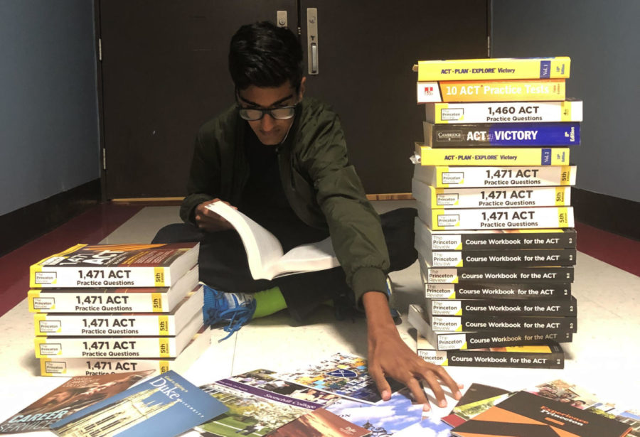 Between stacks of ACT prep books, junior Ronik Bhaskar reaches forward for college pamphlets as he looks towards higher education. Bhaskar earned a 36 on his ACT. “Getting a 36 was a combination of lots of early mornings doing practice tests and a healthy dose of luck,” Bhaskar said.