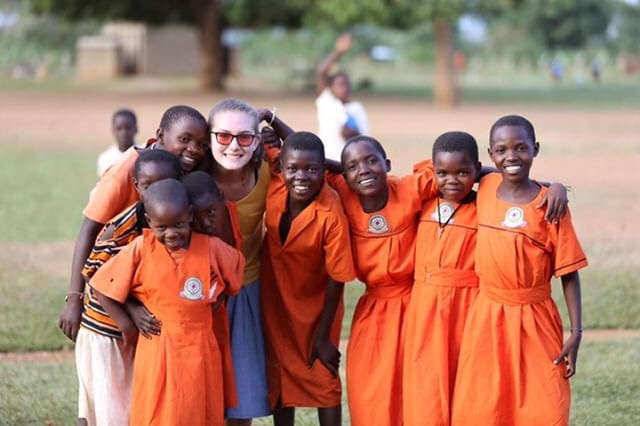 Pausing+to+take+a+photo+with+her+new+friends%2C+sophomore+Megan+Gordon+smiles.+Gordon+shadowed+students+during+her+week+in+Uganda.+%E2%80%9CTo+see+how+they+teach+was+so+interesting%2C+because+the+kids+are+so+well-behaved.+They+teach+in+English%2C+so+I+sat+in+and+we+learned+about+animals+and+their+babies%2C%E2%80%9D+Gordon+said.+The+teacher+gave+them+an+activity%2C+then+left+the+classroom+for+five+minutes.+Everybody+was+sitting+in+their+seats+doing+the+activity+like+perfect+children.+That+never+would+have+happened+in+the+States.%E2%80%9D