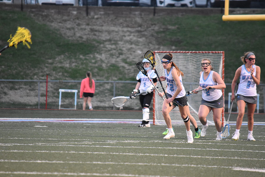 Looking for an open teammate, junior Jenna Mercer travels down the field in a game against Pattonville. The game went into overtime with a score of 6-6 until Mercer scored the game winning goal. “I was so excited and surprised because I didnt think It was going to make it, but then I saw it did and hearing everyone cheer was so exciting,” Mercer said.