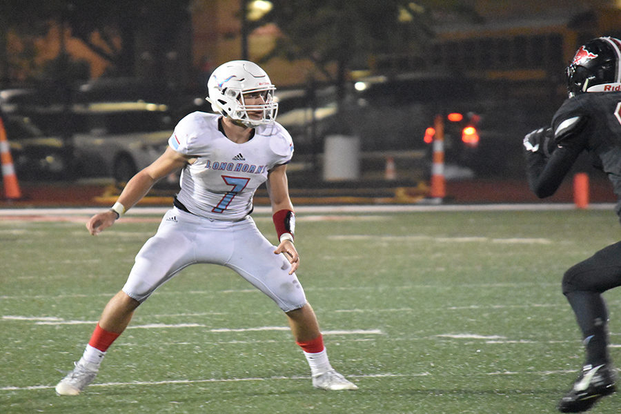 Under the lights of the crowded stadium, senior Jackson Barnhart watches junior Luke Ward make a tackle after a passing the ball to him. Barnhart scored 124 points this season and 1054 rushing yards this season. “I was worried about the running back getting through me and having to make the tackle,” Barnhart said. 

