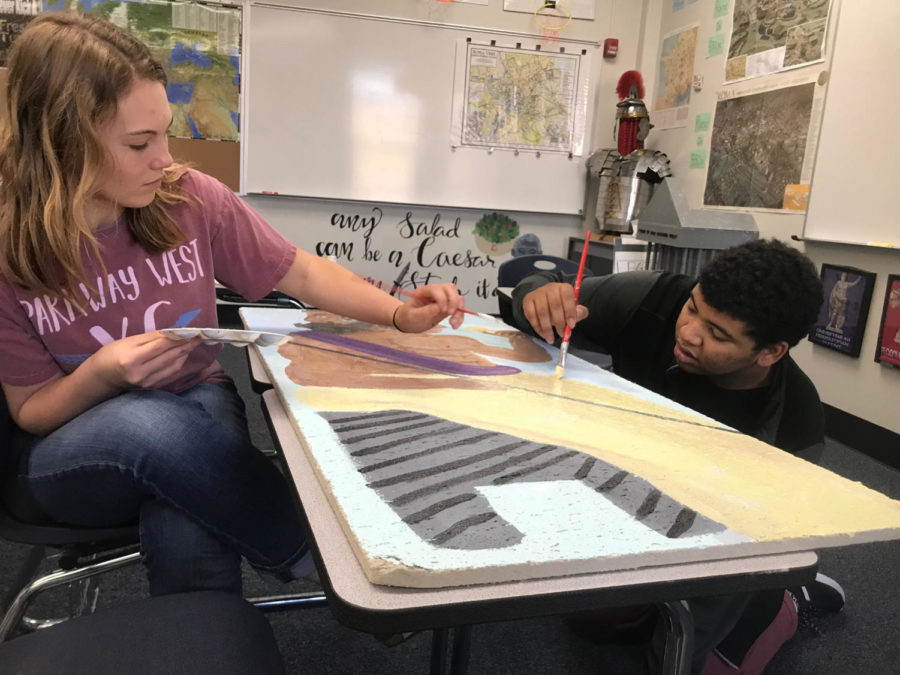 Finishing a tile for Latin teacher Tom Herpel's room, sophomores Emma Smout and Myles Mosley paint. This tile took a year to make and is being finished with the collaborative effort of Smout, Mosley, and sophomore Reese Berry. "My favorite part was making the face because it took so much detail and effort, Mosely said. "But it was really fun to spend times with my friends who I don't have any classes with,"