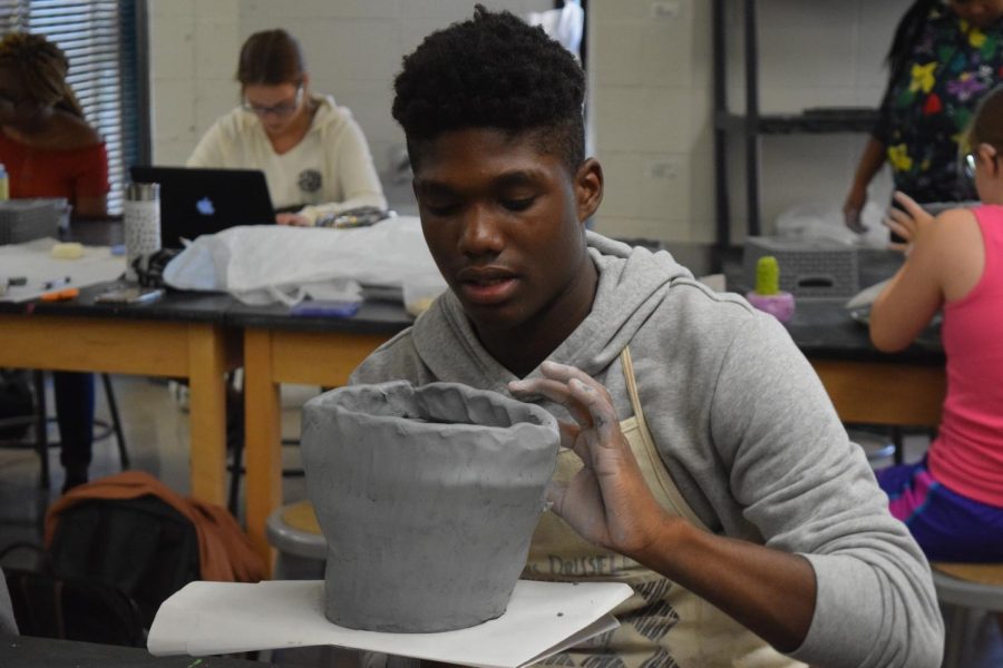 Sitting at his desk, junior Ledaniel Jackson works on builds the base of his ceramic cactus. After the class completed their donuts project, they began creating cactuses for the coil building unit. “I think the best part about the class is having the freedom to create [ceramics] on our own,” Jackson said. “It makes the class really fun.”