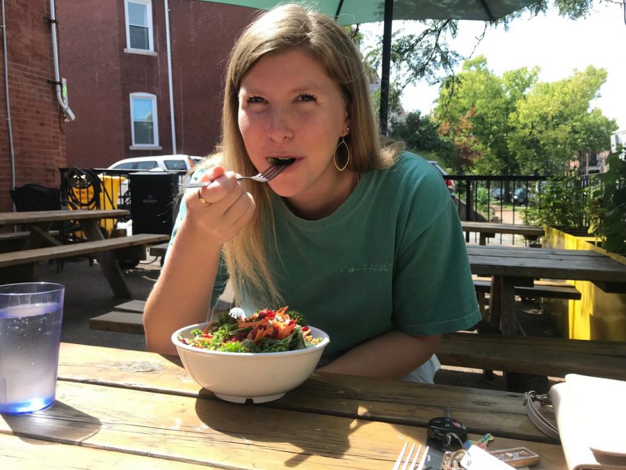 Enjoying the sun on the outdoor patio at Lulu’s Local Eatery, senior Quinn Berry enjoys a vegan kale salad. 
