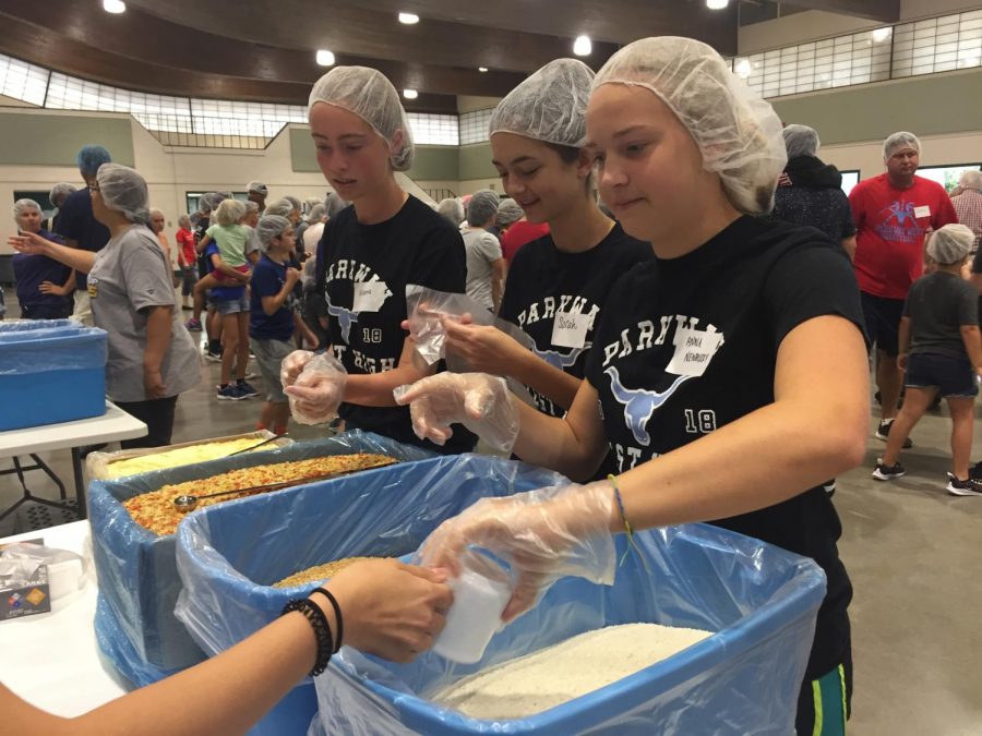 Scooping ingredients to fill the MannaPack, sophomores Aliana Sawall, Sarah Boland and Anna Newberry laugh over spilled rice Saturday, Aug. 17, at Greensfelder Recreation Complex in Queeny Park. Donations to Feed My Starving Children (FMSC) helped to purchase rice, soy, dried vegetables and vitamins, which then got packaged and sent to children in need. “We learned to not yell when one of us spilled something and to communicate better so that no one poured something into the funnel when the bag wasn’t opened yet,” Newberry said. “From this, [I gained] understanding that everyone is different, but we can still find a way to work together and be a unit.” 