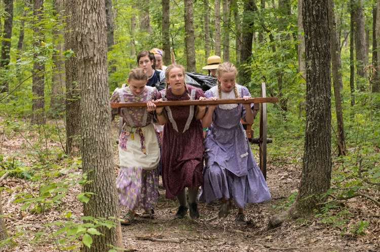 Pulling a handcart through the woods, sophomore Izzie Finlinson (middle) takes part in the women’s pull part of the journey. Many of the pioneers taking the trek lost or had to leave their husbands along the way, so they were the ones who had to pull the carts along the end of the trail. “This pull was a really emotional time for all of us because we were able to put ourselves in those women’s shoes during a time where they really struggled,” Finlinson said. 