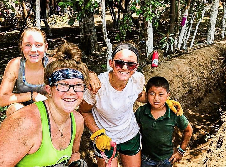 Coated in dirt, junior Reese Berry poses with people in her mission group, Amigos for Christ, and with a child from the village of Espavel. This was Berry’s first mission trip, but she wants to do more in the future. “I think one of the things that really made my heart melt was when one of the Nicaraguans said to us, ‘you dig as though the water will be yours’,” Berry said. 