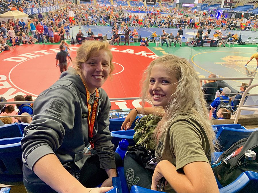 Watching+teammates+wrestle+from+the+bleachers%2C+sophomore+Paige+Wehrmeister+and+teammate+Emma+Cole+bond+through+their+common+interests.+Following+the+trip+to+Fargo%2C+Wehrmeister+continued+to+spend+time+with+the+friends+she+made+during+her+trip+to+Fargo.+%E2%80%9CWe+were+all+representing+the+same+state%2C+and+after+all+that+time+together%2C+I+developed+close+friendships+with+some+of+the+girls%2C%E2%80%9D+Wehrmeister+said.