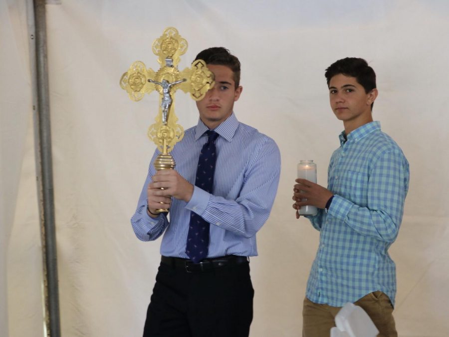 Sandburg High School junior Christian Vouris carries a cross alongside junior Alex Sevastianos during a service. They walked around the outdoor chapel and held the cross while the other campers prayed. “This was morning literacy,” Sevastianos said. “I volunteered to help the priests conduct the service on the last day of camp.” 
