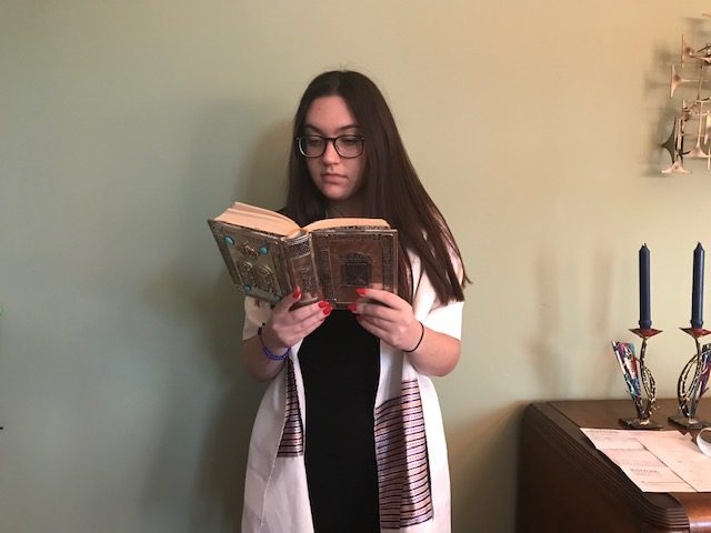 With her tallit (a fringed garment, traditionally worn as a prayer shawl by religious Jews) on and her sidur (prayer book) in hand, junior Sarah Marks participates in the Rosh Hashanah service. Marks is a member at a conservative synagogue, B’nai Amoona.