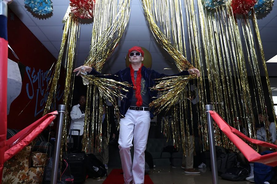 Parting the curtain separating the senior lounge from the senior hallway, senior Nolan Barbre walks the red carpet the morning of Thursday, Sept.12. In honor of the senior class theme for Homecoming week, West Coast Glam, Barbre dressed up as singer/songwriter Elton John. “This has been the best spirit week I’ve seen in all four years, just because of the participation. I see a lot more people participating, everyone’s doing it rather than just the upperclassmen. Glam Day has been my favorite day so far because I got to dress up as Elton John.”