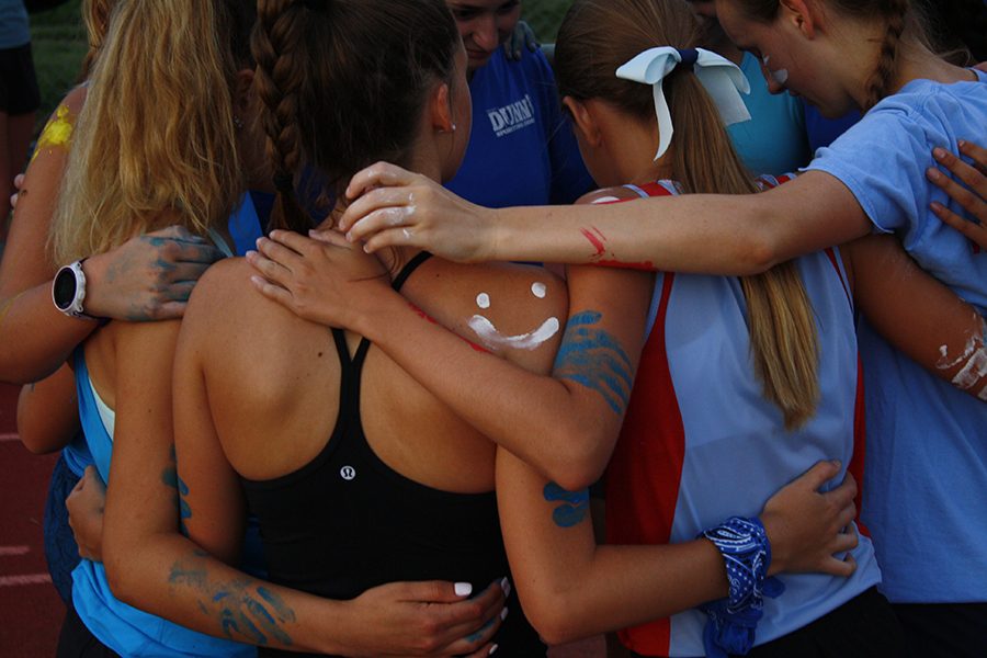 The girls cross country team gathers in a huddle during Red and Blue Night.