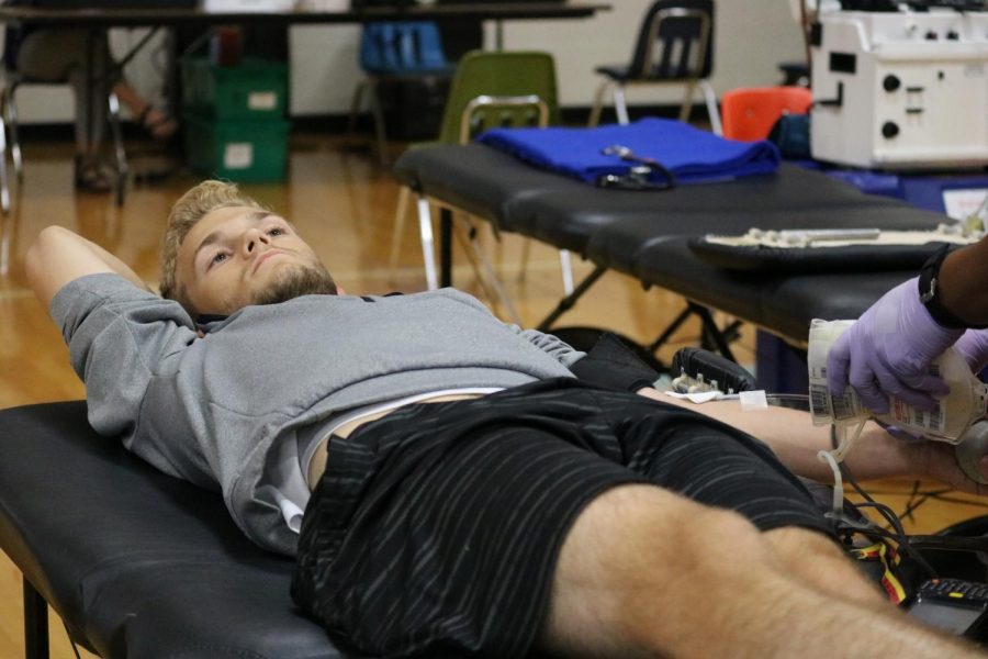 Waiting for his blood to fill the bag, senior Bailey Mosher donates blood at the Red Cross Blood Drive Oct. 5. The event was organized by the Red Cross Club, and donors ages sixteen and up could participate. “I thought it would be helpful to donate. I knew a lot of people from West wouldn’t be able to, and we didn’t have a lot of time to spread the word,” Mosher said. “You save around three lives just by donating blood, so it’s a cool thing to do to help other people.”