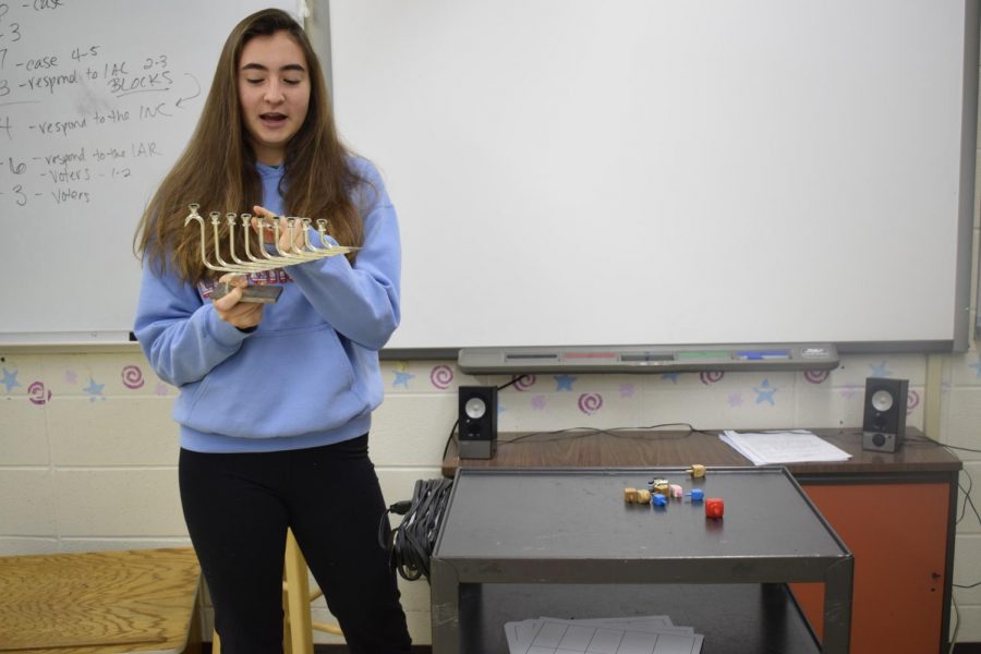 Pointing+to+the+fourth+branch+on+the+Chanukiah%2C+junior+Ella+Seigel+describes+Chanukah+and+other+Jewish+holidays+to+her+peers.+Seigel+presented+with+props+to+share+part+of+the+Jewish+culture+with+students+at+Westminster.+%E2%80%9CTheir+engagement+showed+that+if+you+open+up+and+show+your+differences%2C+that+can+also+provide+unity+in+understanding%2C%E2%80%9D+Seigel+said.