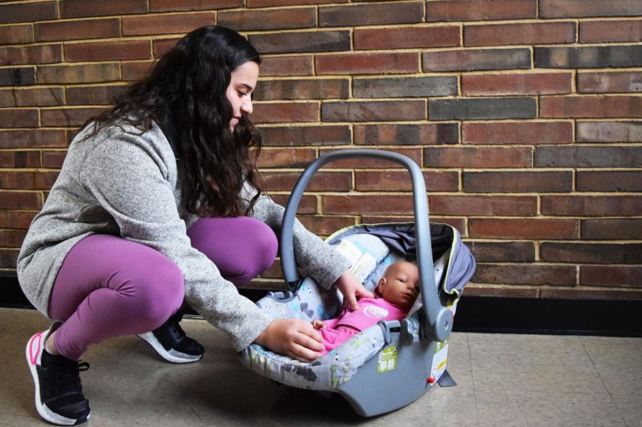 Freshman Sarah Griege puts her interactive baby into its car seat. Working under pressure was important in caring for the baby when it cried. "I just kind of had to stay calm," Griege said. "When I was trying to figure out what was wrong and care for it in time, I just didn't let the crying distract me."