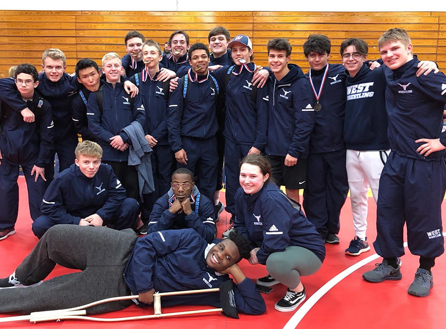 Celebrating their success, boys wrestling poses for a team picture after a long day of matches, junior Tim Nelson lays in front of the team, holding his crutch in his hand. “It’s definitely disappointing, missing out on this season,” Nelson said. “Even though I can’t play, I still want to make the most of this season with my teammates.”