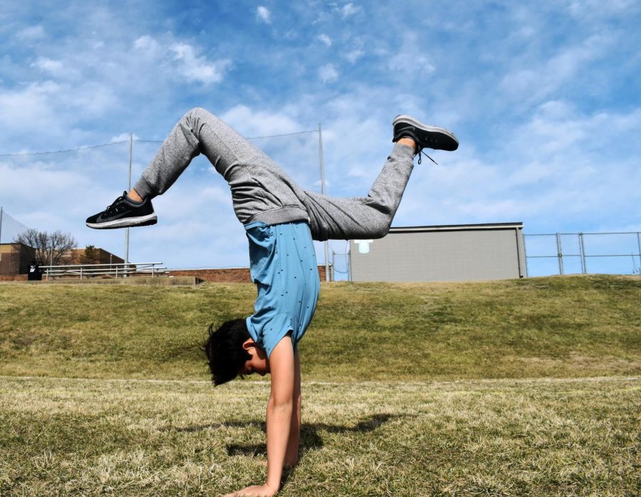 Freshman Tristan Caudill practices a handstand in a field.  Caudill pushed to try new things even when they seemed intimidating. “My coaches always tell me ‘get comfortable with being uncomfortable,’” Caudill said. “A lot of what youre going to do is stuff that you will not be comfortable with, but if you dont get comfortable with that, youre not going to progress at all.