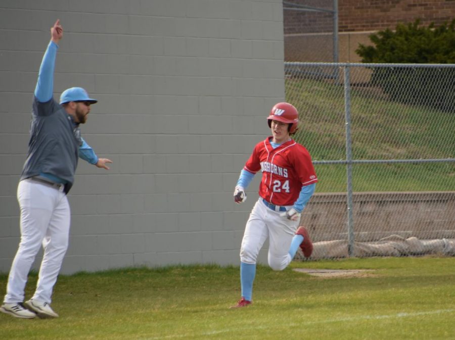 Junior varsity baseball coach Andrew Jett swings his arms while coaching third base telling senior Jason Reilly to run to home plate.  Jett feels at home when coaching baseball. “ I hope that in 10 years I meant so much to them that they invite me to their weddings,” Jett said.