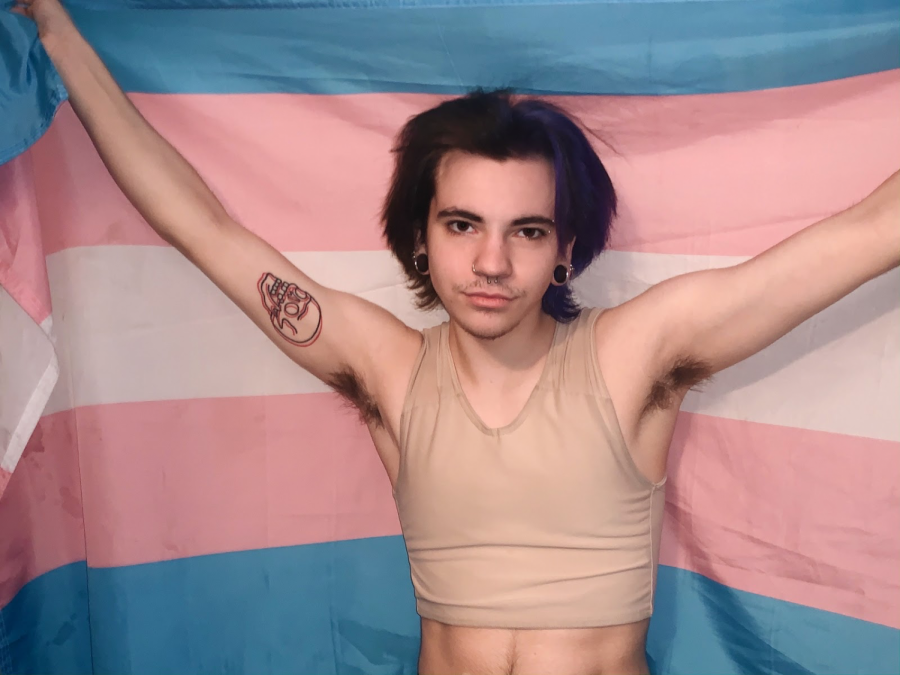 Holding+up+the+transgender+pride+flag%2C+senior+Tony+Morse+takes+a+picture+in+his+binder.+He+got+the+flag+towards+the+end+of+middle+school.+%E2%80%9CThe+flag+for+me+is+a+symbol+of+pride%2C%E2%80%9D+Morse+said.+%E2%80%9CIt+reminds+myself+and+others+of+who+I+truly+am.+I+am+wearing+a+binder+in+my+photo%3B+I+used+to+be+very+very+self+conscious+of+letting+others+know+I+used+a+binder.+Now%2C+I+am+comfortable+enough+to+post+pictures+of+me+in+it+and+wear+it+out+in+the+open.+I+feel+as+if+I+pass+enough.+Once+I+get+top+surgery%2C+I+am+so+excited+to+not+have+to+deal+with+wearing+the+chest+binder.+It+definitely+takes+a+toll+on+me+having+to+wear+it.+It+gets+physically+uncomfortable+and+I+long+for+the+day+when+I+can+put+on+a+shirt+without+having+to+put+it+on+first%2C+as+well+as+being+able+to+take+off+my+shirt+and+be+proud+and+comfortable.%E2%80%9D