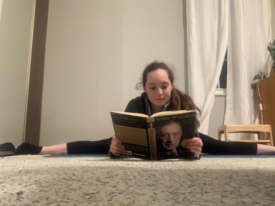 Multi-tasking to make the most of her time, sophomore and gymnast Paige Matthys-Pearce stretches and reads to learn about leadership. 
