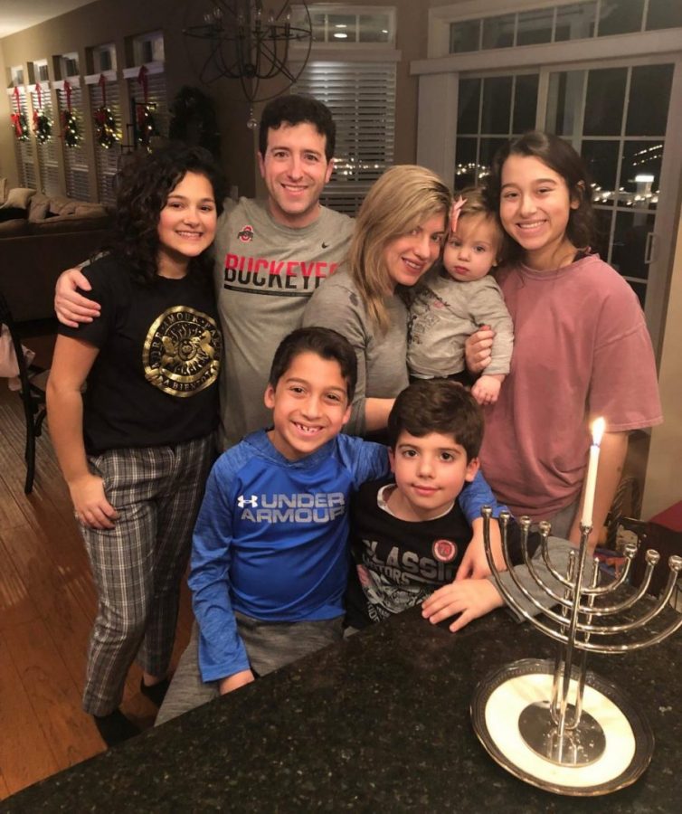 Posing next to a menorah with her siblings, cousins and aunt and uncle, junior Devyn Green celebrates Hanukkah 2019. Green, being her family’s eldest child, lit the candle on the menorah for the first night of the celebration. “[Hanukkah] is an important holiday,” Green said. “It’s cool to celebrate something other than Christmas, and there’s a blessing that comes with it.” 