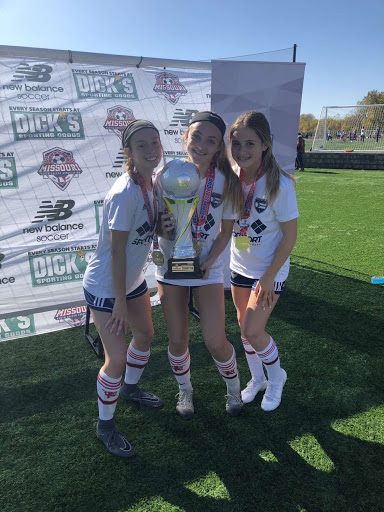 Posing with the State Cup, sophomore Cate Adler and teammates celebrate before attending their traditional team dinner. Off the field bonding was crucial to improving their game play. My team and I are really close. Hanging out when we go out of town is one of our favorite things to do, Adler said.