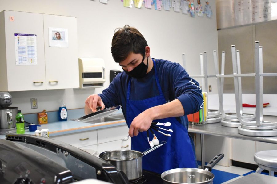 Adding salt to the water, senior Donald Mahoney carefully measures ingredients to cook pasta in his Let’s Cook Together class Feb. 23. Mahoney took the class to improve his cooking skills, and so far the biggest challenge has been making sure he has everything he needs. “My favorite recipe is the no-bake cookies we made once,” Mahoney said. “I just love all of our cooking days.”