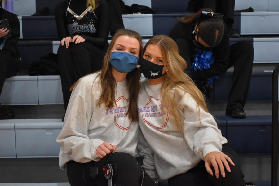 Cheering on their fellow poms teammates, sophomores Allie Byergo and Cameron Chandler attend a varsity boys basketball game Jan. 8. Because of their injuries, Byergo and Chandler were not able to participate in any dancing. “Its actually pretty fun to get to go to the games since not a lot of people can right now because of COVID-19,” Byergo said. “Ever since Ive been injured, even though I havent been able to dance, its been really good to still be a part of the team and still be able to wear poms clothes and go and represent at games.”