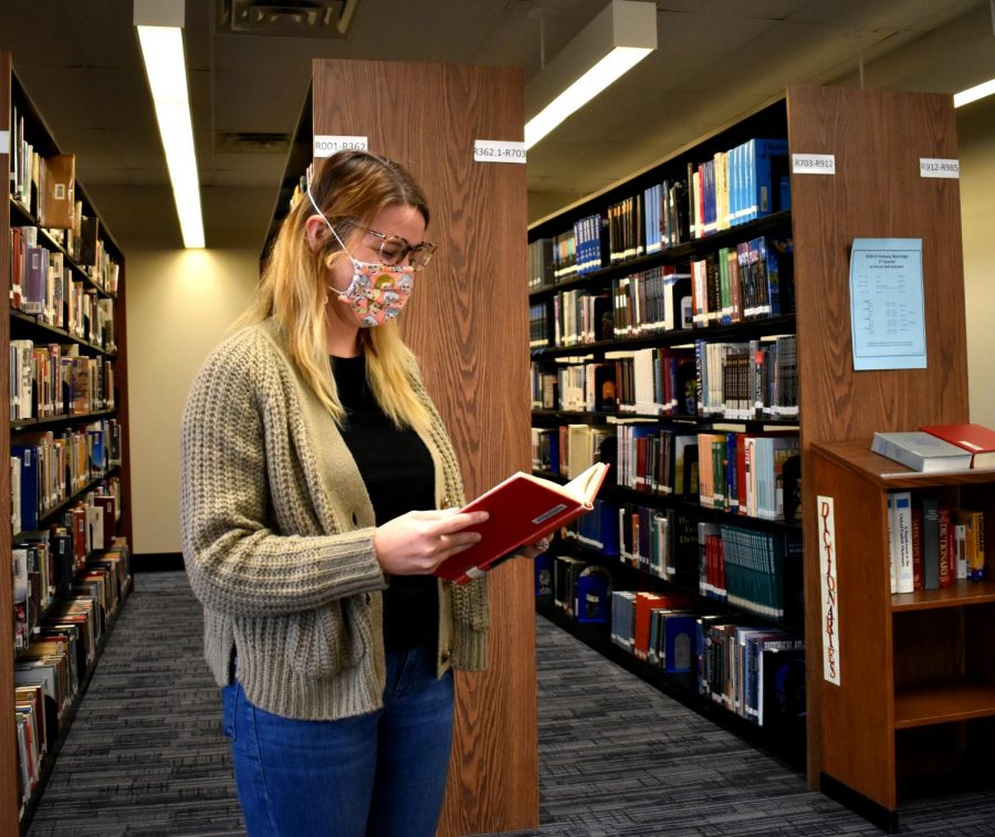 Wearing a cardigan and blue jeans, librarian Lauren Reusch reads a book in the library. Reusch realized she typically wore the same few pieces of clothing, and has since committed to not buying new clothes for six months. “You know your favorite pieces that make you feel good,” Reusch said. “The majority of the time I spend at home or with family I wear sweats.”