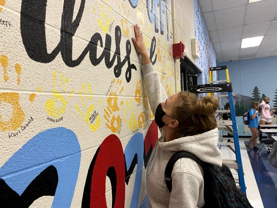 Reaching her hand up the wall in the cafeteria, senior Bella Allgeyer places her handprint among the others. The senior hand wall is a long-standing Parkway West tradition. I like that the mural subtly represents everything weve been through in the past year, Allgeyer said. The senior hand wall tradition means a lot because we are imprinting our impact on the school, kind of as a sign of remembrance for our entire class.