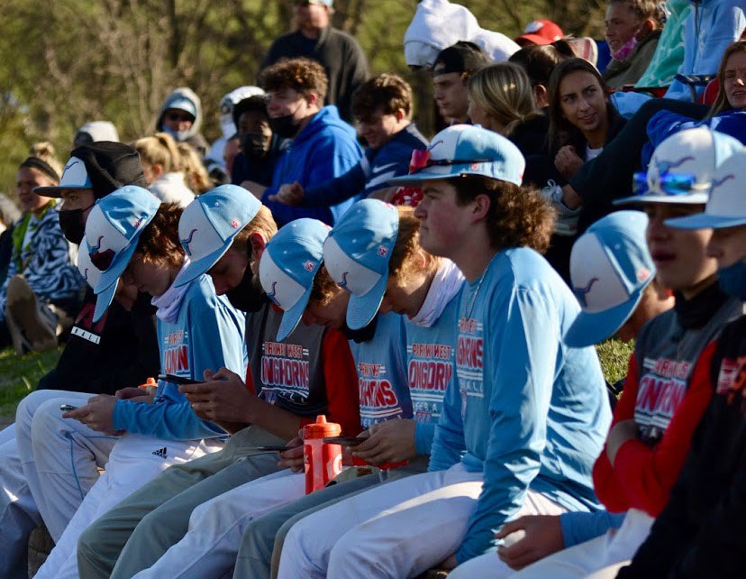 Lined up on the brick wall behind the baseball field, fans and younger players sit and watch varsity defeat CBC 16-6, Wednesday, March 31. The team rallied for eight runs in an explosive fifth inning, leading to an inevitable mercy-rule finish after five innings. “The student section at baseball games was really laid back and a lot of fun as we talked about the game more and explained certain situations to people who were confused or interested in learning,” senior fan Carson McCormack said. “The fans were able to be around the great weather and talk with friends.”