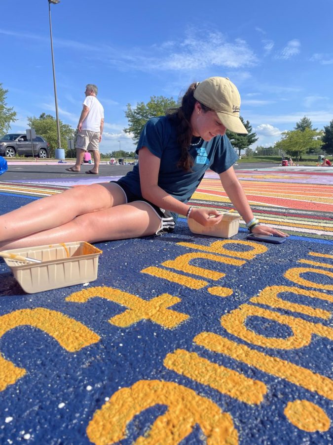 Painting the letters of her parking spot, senior Paige Matthys-Pearce participates in painting day. Matthys-Pearce painted a starry background with a quote written in French, which says ‘don’t forget who you are.’ “Im happy that I got to participate in this new tradition because I think its a great way for us seniors to leave a mark here, even though the spots will get painted over at the end of the year. Pulling into the colorful parking lot each morning brings me so much joy, and all the different designs highlight how unique everyone is,” Matthys-Pearce said. “Even though we sat under the sun in a hot parking lot for seven hours straight, it was a fun experience that I hope future classes will continue.”