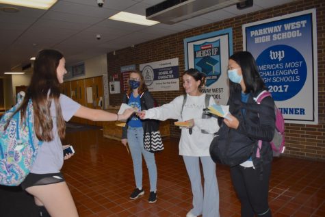 Greeting students with a poem and a smile, junior Nicole Imral hands out one of many pocket-sized poems in her stack. Spread out near the school entrances, Imral and several other National English Honors Society (NEHS) members informed students and staff about the day and handed out poems. “I love poetry. I was excited about [Poem in Your Pocket Day] because its fun to read a bunch of different poems youve never read before, especially short ones because its easier to get through them,” Imral said.