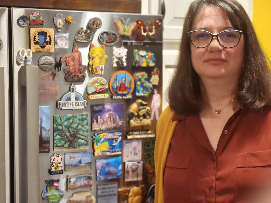 Athletic and Activities Secretary Gina Groceman stands in front of her magnet-covered fridge. Groceman has collected magnets from Canada, Mexico, Luxemburg, Germany, Belgium, the Netherlands, England and Japan. “I bet I have at least 100,” Groceman said.