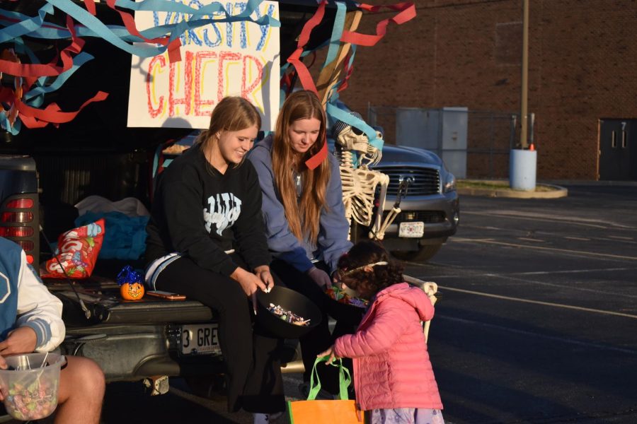 Seniors Abigail Wheeler and Grace Fotheringham hand candy to a princess at the varsity cheer trunk. Fotheringham helped decorate with streamers and loved interacting with kids and seeing their costumes. I love kids, and it [was] a great way [for them] to get involved at West. It was such a cute idea, Fotheringham said.
