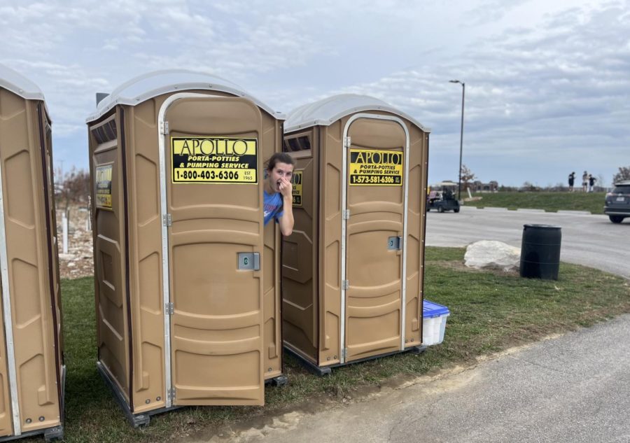 Holding her nose, senior Kennedy Whitaker peeks out of a porta-potty. Porta-potties were created to save time as temporary toilets — perfect for cross country meets. “They are very [beneficial] for my running because they allow me to feel good and not have to go to the bathroom when I run,” Whitaker said.