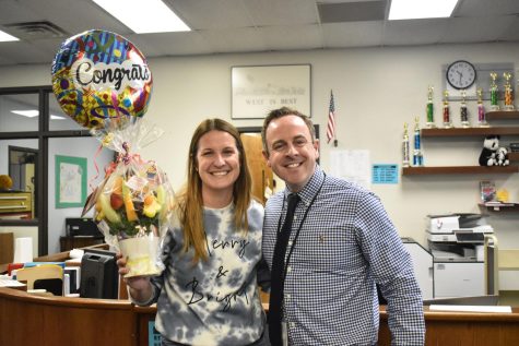 Librarian Lauren Reusch holds her Edible Arrangements flower bouquet and poses with principal John McCabe after announcing her winning Teacher of the Year.