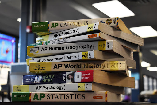 A pile of Advanced Placement (AP) study books sit on a library desk. When taking AP classes, many students sacrifice other areas of their lives to keep their grades up. “Its not the fact that I am taking an AP class. I am spending more time doing the work for school than I would spend time with friends and family,” senior Noah Schell said. “It is a sacrifice I made and realized after signing up for the classes. Over the years, I have devised a system of managing my time, which sometimes means I don’t get all of the work done.” 