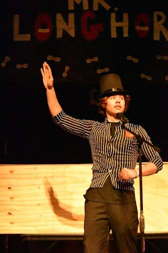 Holding his hand high for the audience to see, senior Joey Schweppe performs an illusion during the Mr. Longhorn pageant. Schweppe’s acted as a magician for the night, re-enacting the magic scene from Diary of a Wimpy Kid. “I wanted to engage the audience by doing something different. This night was one of the landmarks for senior year. It’s scary because college is going to be a new experience, and then we are adults, but it’s exciting at the same time,” Schweppe said. 