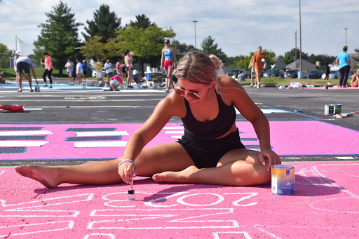 Senior Cameron Chandler sits in a sun-lit parking space, adding finishing touches to her senior parking spot. Chandler’s design for her spot read, ‘hop in, we have one more year.’ “It’s a quote from ‘Mean Girls,’ and since I drive a convertible, I figured it was fitting. [Senior Ashlynn Ware’s] spot is right next to mine, and she has a ‘Mean Girls’ quote too. They’re refreshing and funny to start my morning reading,” Chandler said. 
 